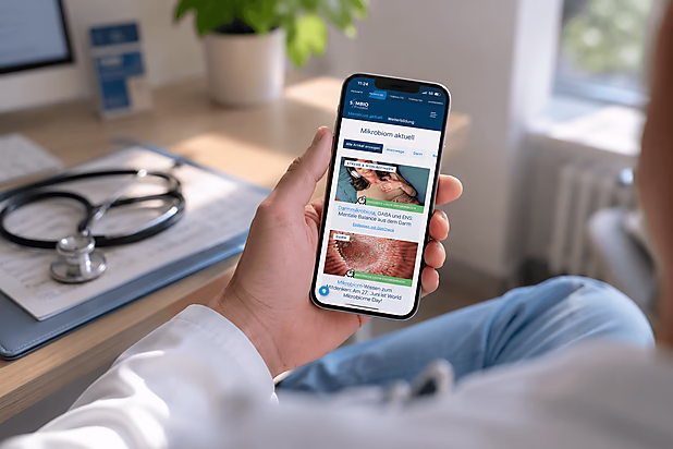 Ein Arzt hält ein Smartphone, auf dem Informationen über das Mikrobiom angezeigt werden. Im Hintergrund ist ein Stethoskop sichtbar.